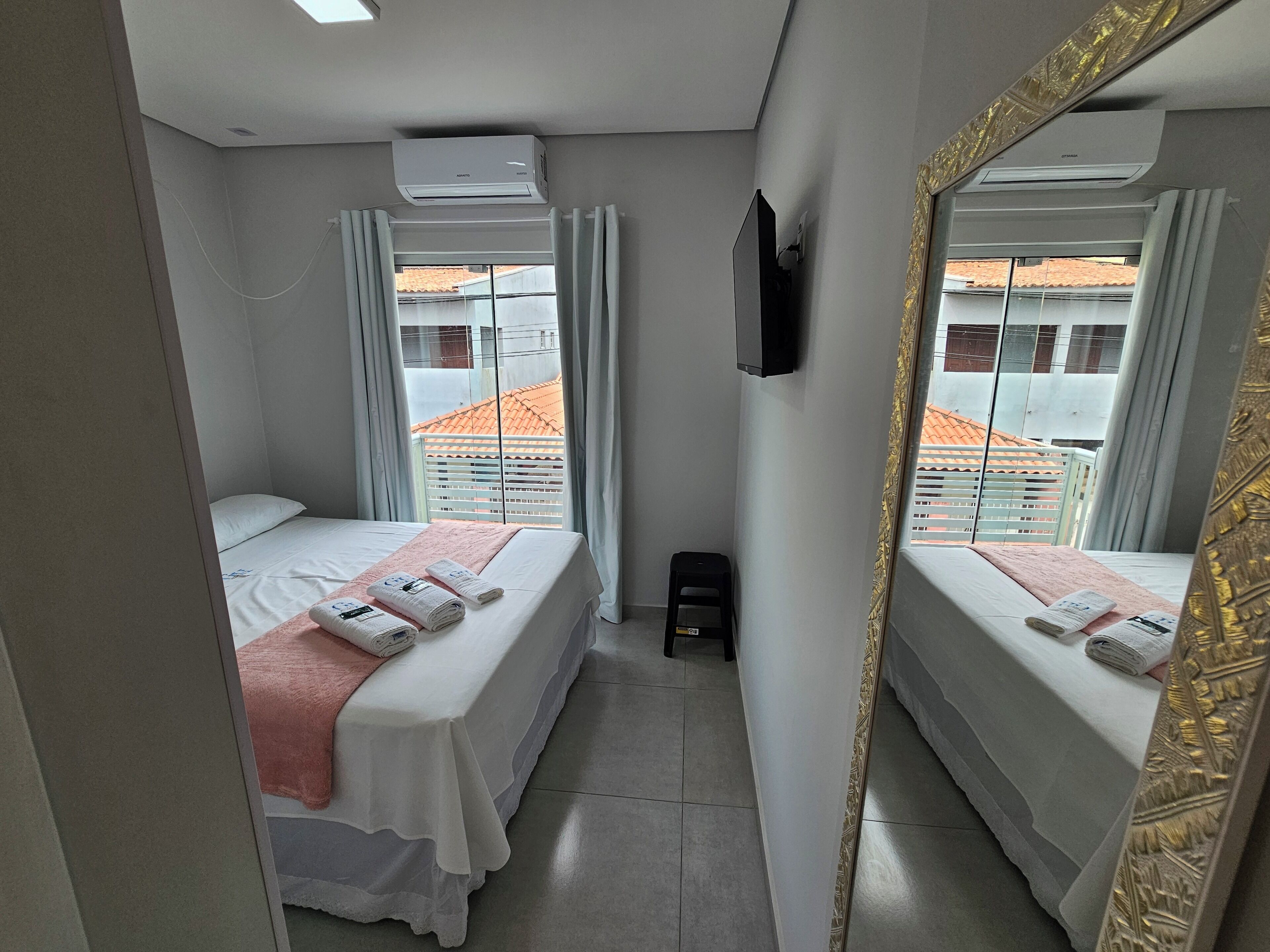 Habitación de hotel con dos camas, televisión y vistas a un edificio de tejado a ladrillo.