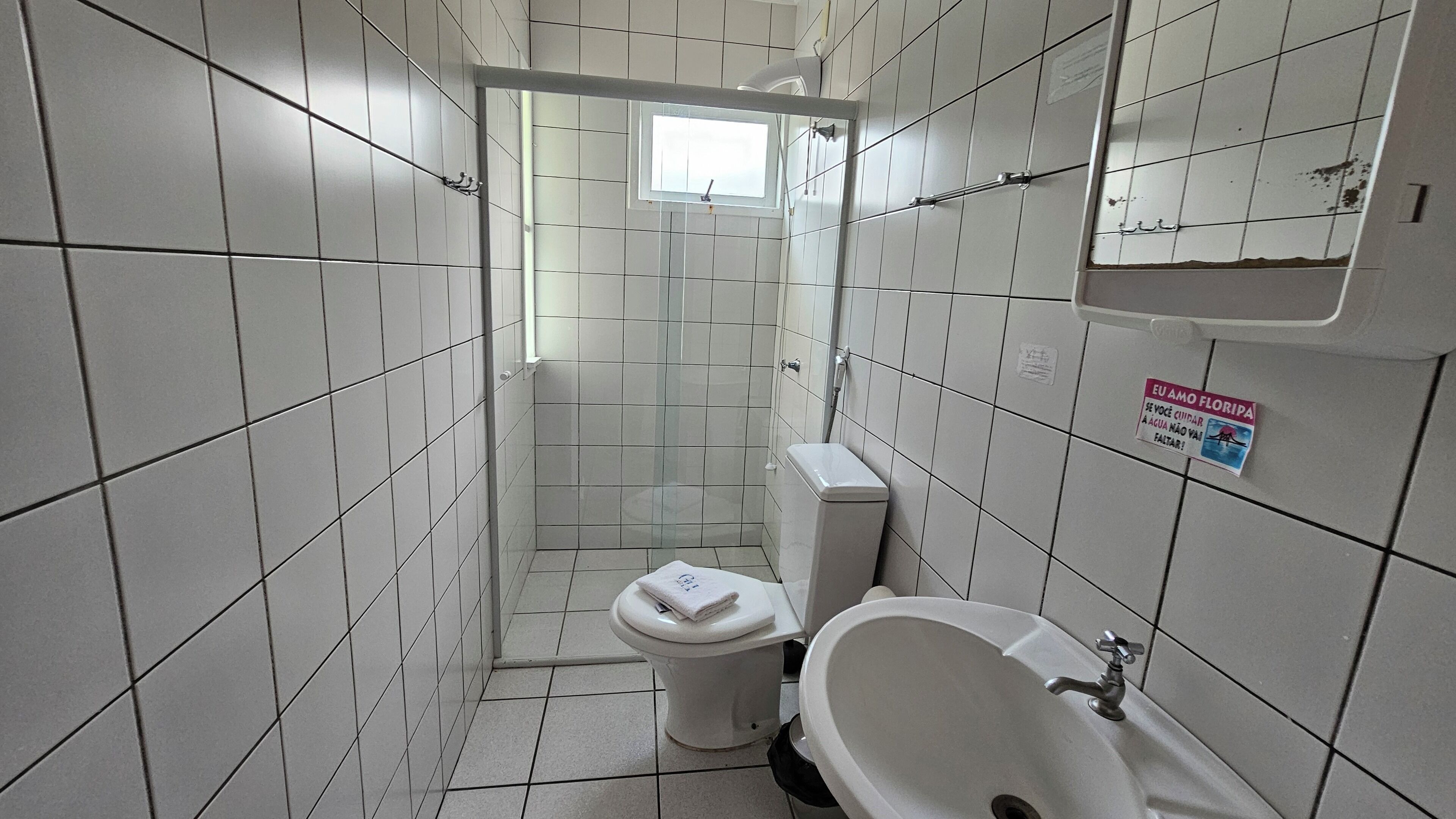 Ein kleines Badezimmer mit Fliesen, Toilette, Waschbecken und Dusche.