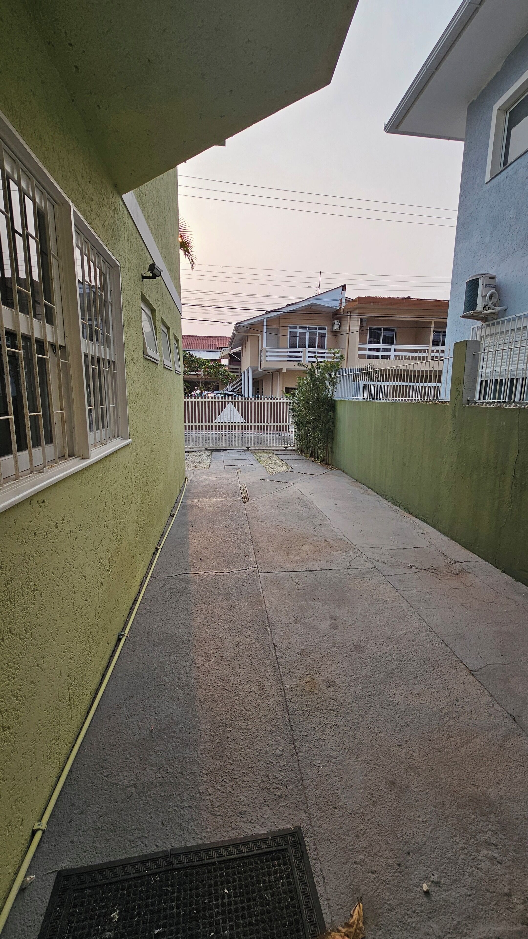 A narrow alleyway with a gated entrance leading to a building with barred windows.