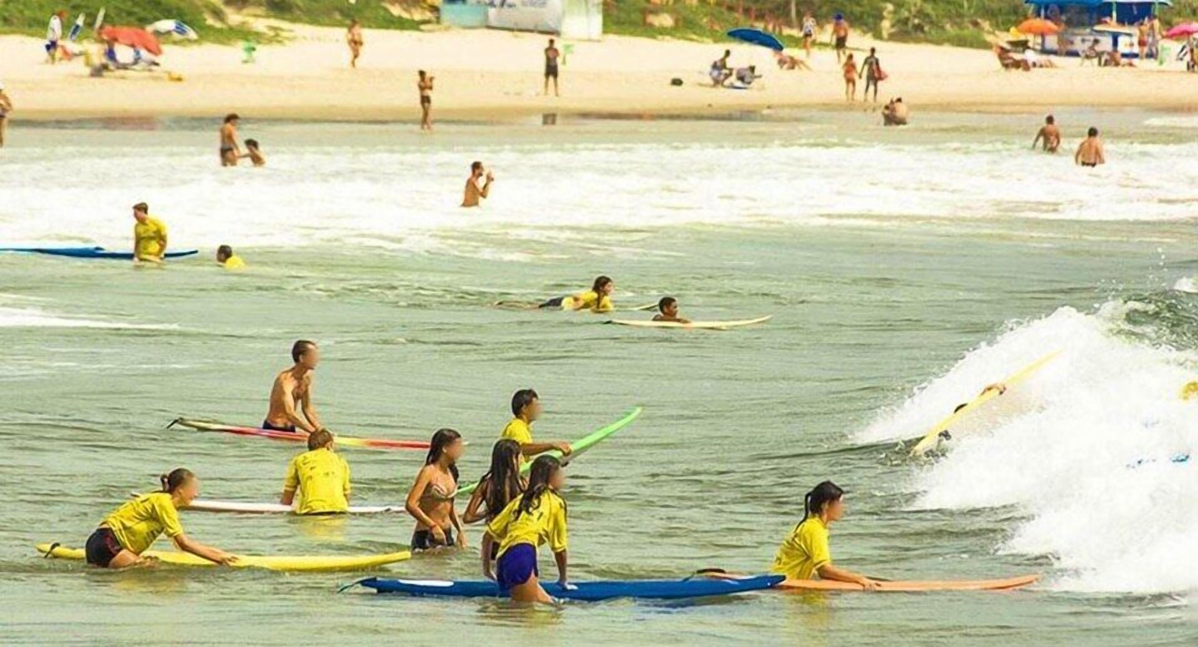 A beach with people on surfboards and swimming in the water.