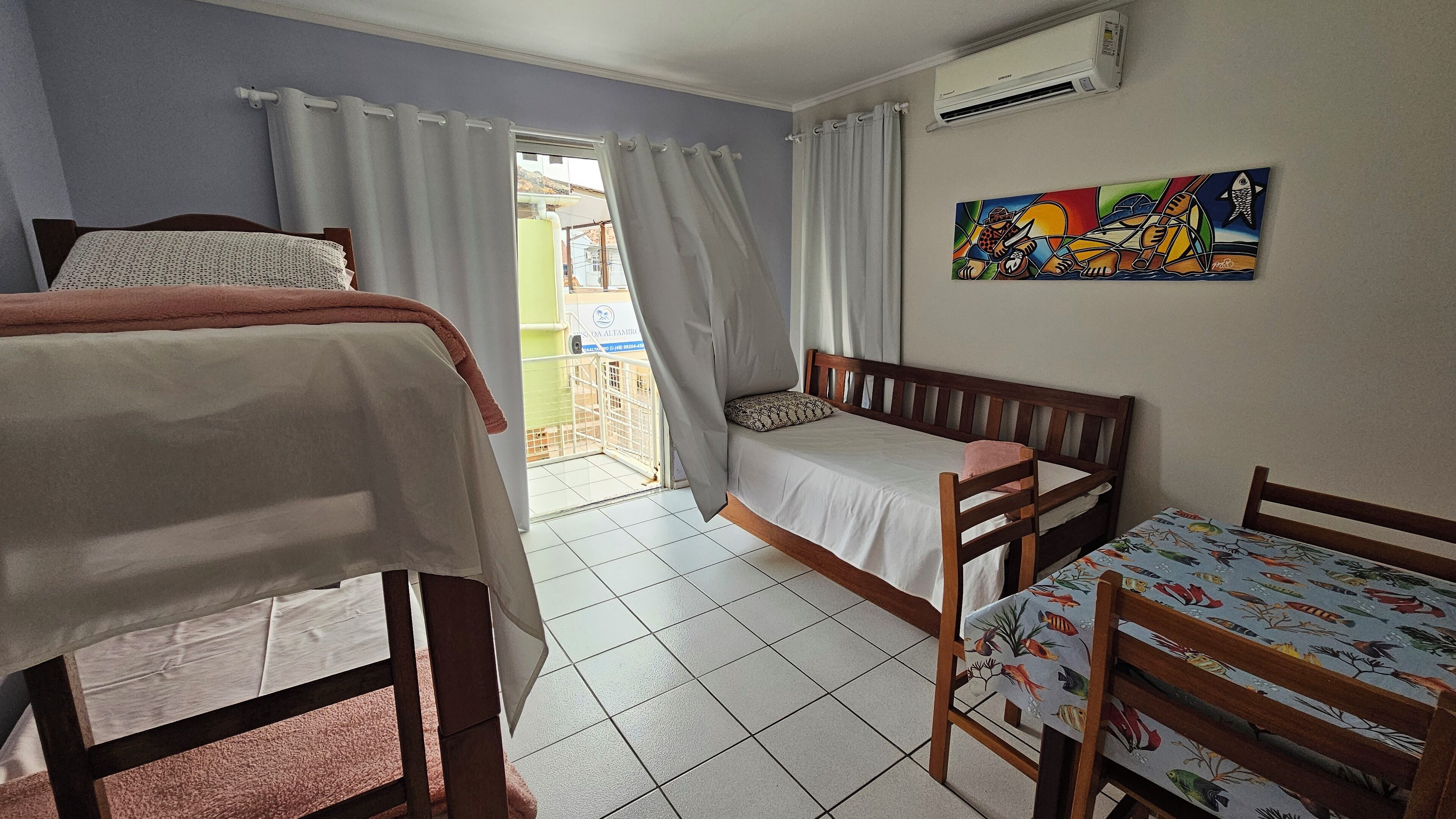 A room with a bed, a chair, a table, and an air conditioning unit.