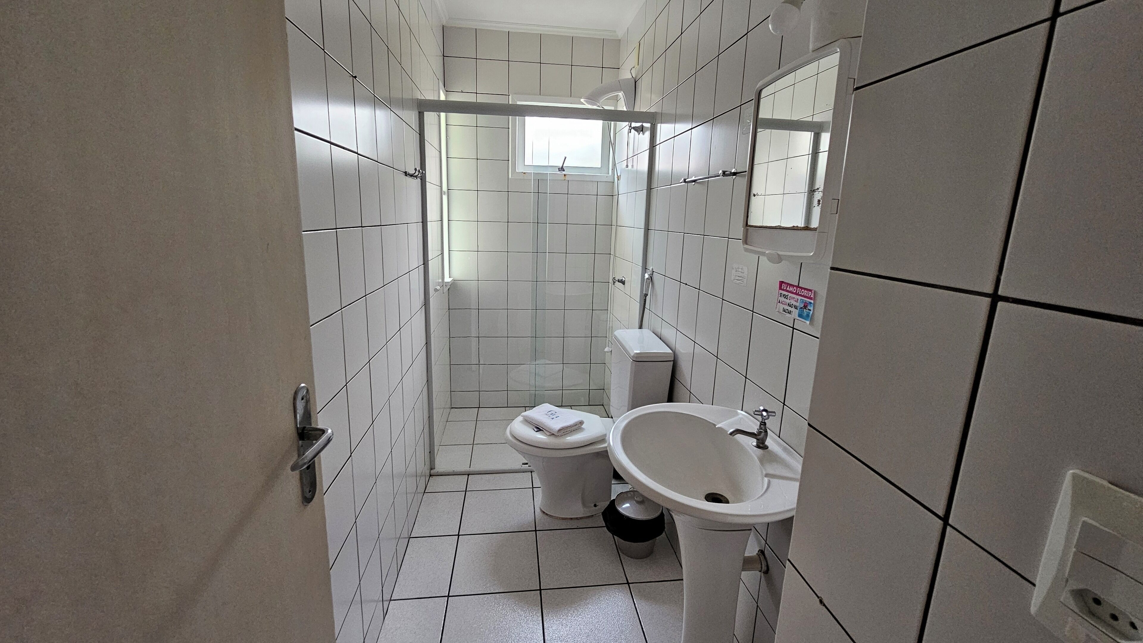A small, tiled bathroom with a toilet, sink, and shower.