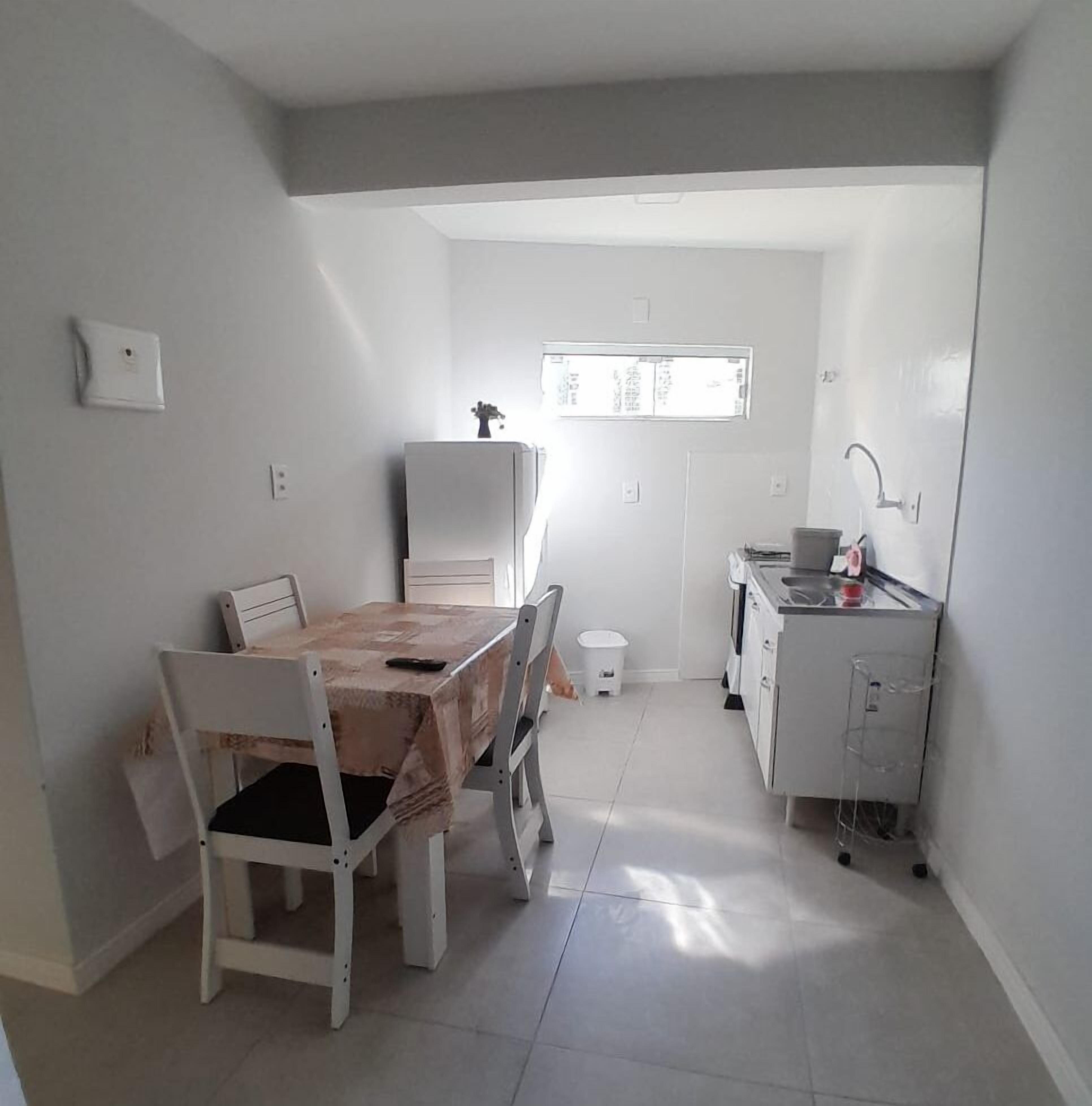 A compact kitchen with a dining area, white cabinetry, and a small window above the sink.