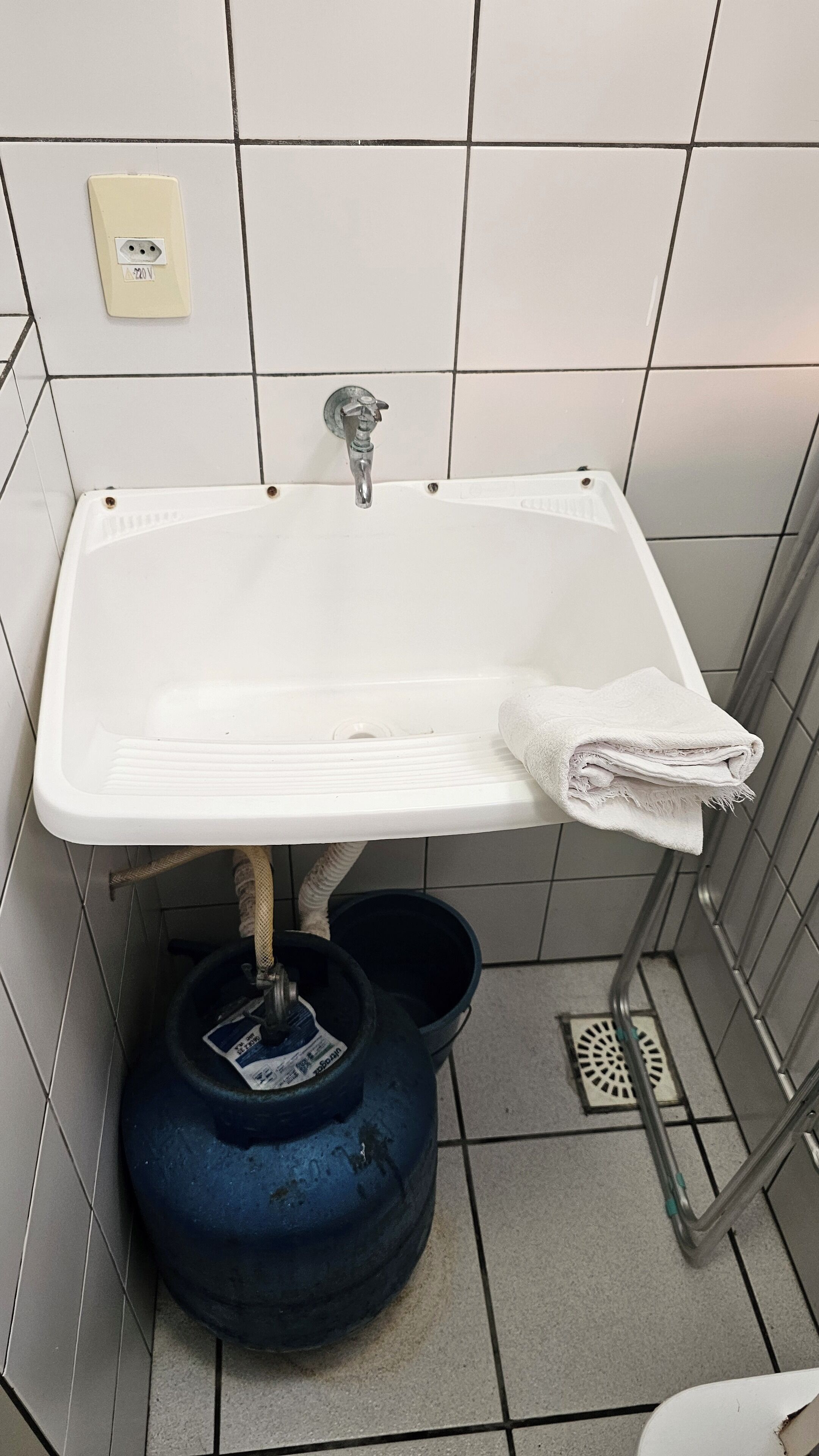 Un baño con un lavabo blanco, una toalla y un calentador de agua azul.