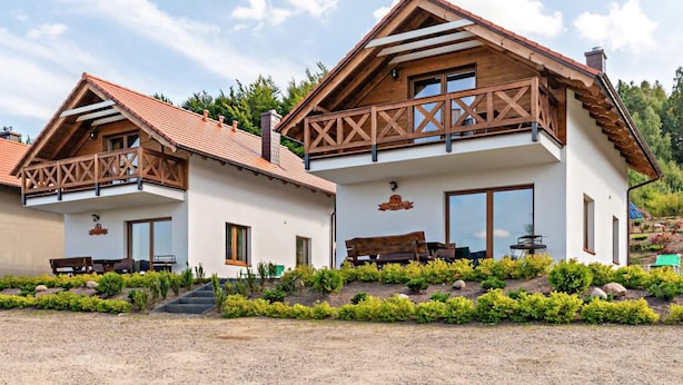 Zwei Chalets im Chalet-Stil mit Holzbalkonen, großen Fenstern und einem gepflegten Garten.
