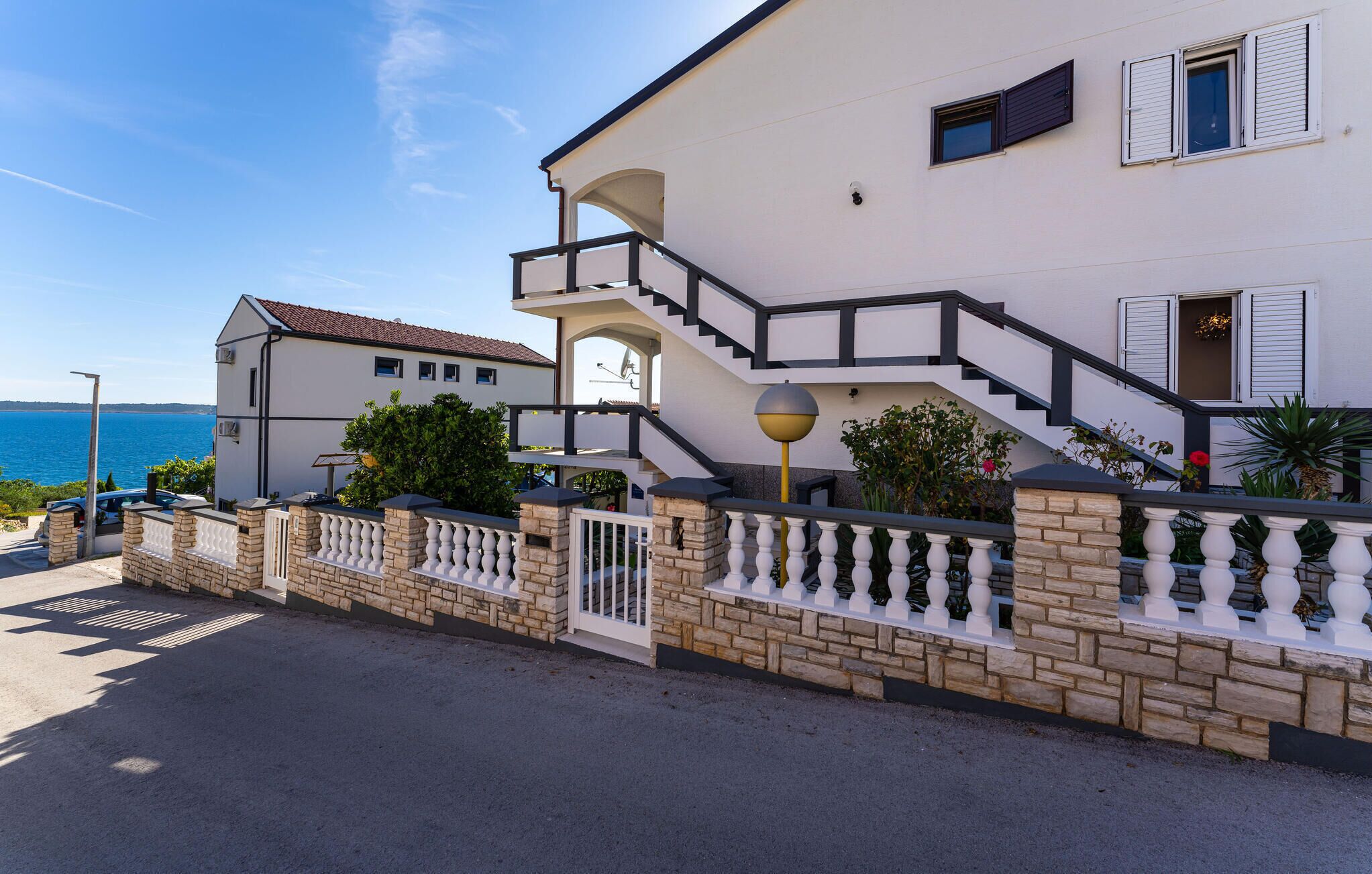 Une maison à deux étages avec une façade en pierre, un balcon et une vue sur la mer.