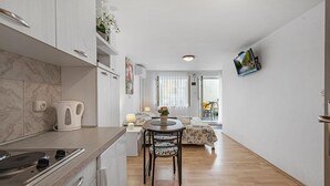 Une cuisine moderne équipée d’une cuisinière, d’une bouilloire et d’un coin repas avec une table et des chaises.