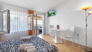 Une chambre d’hôtel avec un lit, une table et des chaises, un téléviseur et une lampe sur pied.