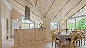 Une cuisine spacieuse aux murs en bois et dotée d’un grand îlot central, avec une cuisinière moderne et un vaste plan de travail.