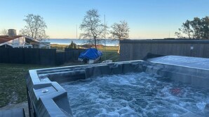 Un jacuzzi avec vue sur l’océan et une cour arrière dotée d’un patio couvert et d’une clôture en bois.