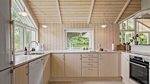 Une cuisine moderne avec des murs recouverts de panneaux en bois, une grande fenêtre et des appareils électroménagers intégrés.