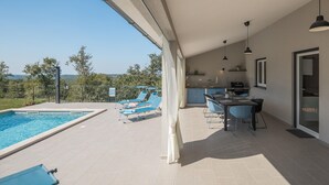 Un espace extérieur abrité comprenant une piscine, des chaises longues, un bar et une cuisine.