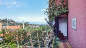 A balcony with a view of the sea and a building with a pink wall. - Lovely apartment in Trabia with house sea view (Trabia)