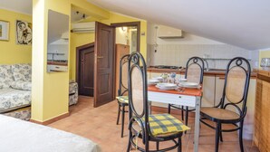 A compact kitchen with a dining area, featuring a dining table with chairs, a sofa, and a kitchen counter. - Lovely apartment in Trabia with house sea view (Trabia)