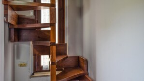 A spiral staircase with wooden steps and handrails, leading to a landing with a window. - Lovely apartment in Trabia with house sea view (Trabia)
