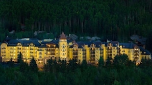 A large, multi-story hotel with a central tower, surrounded by dense forest. - Vail Ritz Carlton 3 Bedroom Residence (Vail)