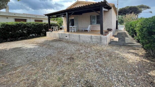 A small house with a covered patio, a gravel driveway, and a garden area. - Maison de 2 Chambres Pour 4 Personnes (Marseillan)