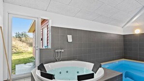 Un baño moderno con una bañera grande, zona de ducha y una pequeña piscina.