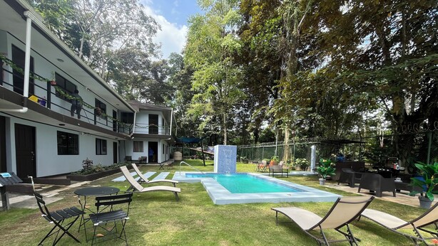 A pool area with lounge chairs, a barbecue grill, and a fenced garden. - Hotel Azul Coral (Cahuita)