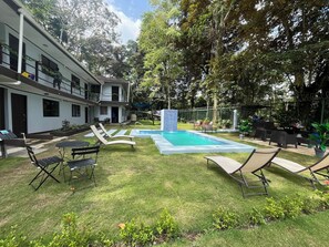 A pool area with lounge chairs, a barbecue grill, and a fenced garden. - Hotel Azul Coral (Cahuita)
