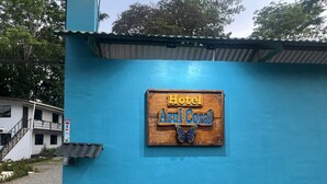 A blue building with a wooden sign that reads "Hotel Azul Coral" and a butterfly decoration. - Hotel Azul Coral (Cahuita)