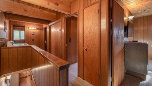 Un interior de madera con una cocina, una encimera y una puerta que da a otra habitación.