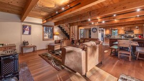 Un amplio salón con techo de madera, un sofá, una mesa de centro y una chimenea.