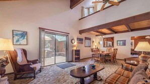 A spacious living room with a large window, a dining area, and a cozy seating area.