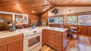 A kitchen with wooden cabinets, a stove, and a dining area with a table and chairs.