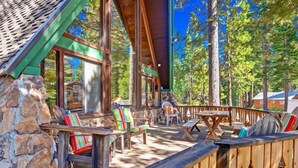Une terrasse en bois avec des murs en pierre, des sièges d’extérieur et une vue sur les arbres.