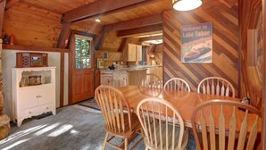 Un intérieur en bois comprenant un coin repas, une cuisine et un panneau indiquant la bienvenue au lac Tahoe.