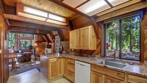 Une cuisine spacieuse dotée de meubles en bois, d’un plan de travail en granit et d’une grande fenêtre donnant sur l’extérieur.