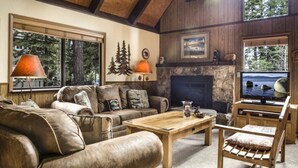 A cozy living room with a stone fireplace, leather sofas, and a wooden coffee table.