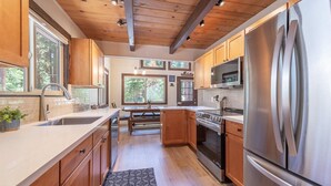 A modern kitchen with wooden cabinets, stainless steel appliances, and large windows. - Agate Bay Pines (Carnelian Bay)