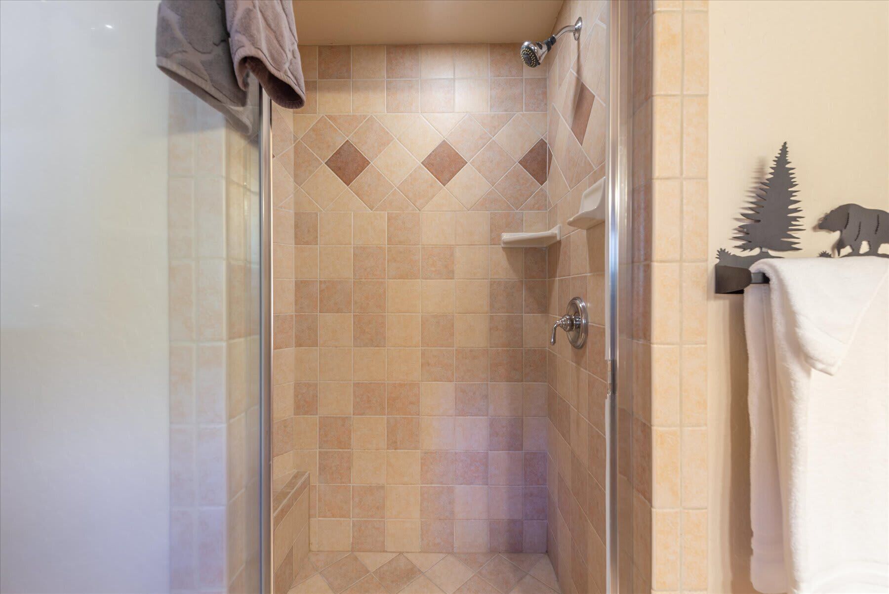A glass-enclosed shower with beige tiles and a showerhead.