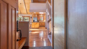 Interior de madera con cocina, suelo de madera y vistas al exterior.