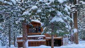 A wooden cabin with a balcony, surrounded by snow-covered trees. - Evans Cabin (Carnelian Bay)