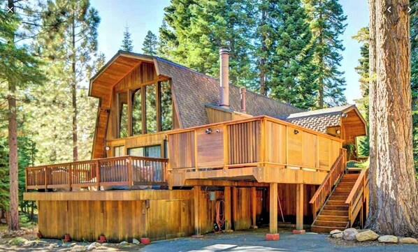 A wooden cabin with a deck, large windows, and a chimney. - Evans Cabin (Carnelian Bay)
