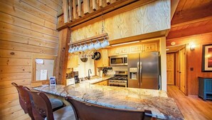 A kitchen with wooden walls, a marble countertop, and modern appliances. - Evans Cabin (Carnelian Bay)