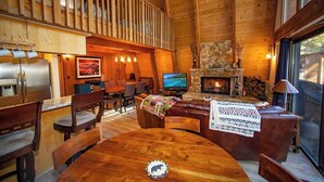 A cozy cabin interior with a wooden dining area, a fireplace, and a television. - Evans Cabin (Carnelian Bay)