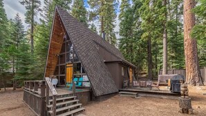 A cabin with a sloped roof, wooden deck, and a small porch. - Sunshine Cabin (Carnelian Bay)