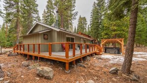 A cabin with a wooden deck, a hot tub, and a covered seating area surrounded by trees. - Triple C, Private Hot Tub, Dog-Friendly (Carnelian Bay)