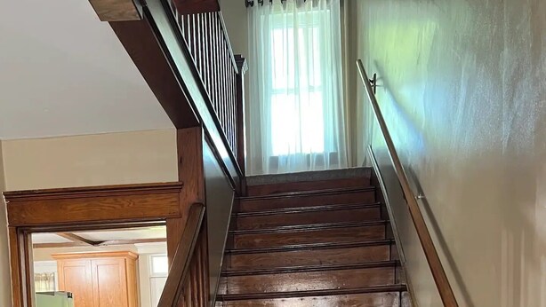 A wooden staircase with a handrail, leading to a room with a window and a door. - Millheim Mallard Place (Millheim)