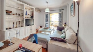 A living room with a sofa, a TV, and a dining area with a table and chairs. - 2 bedroom stunning apartment in Nerja (Nerja)