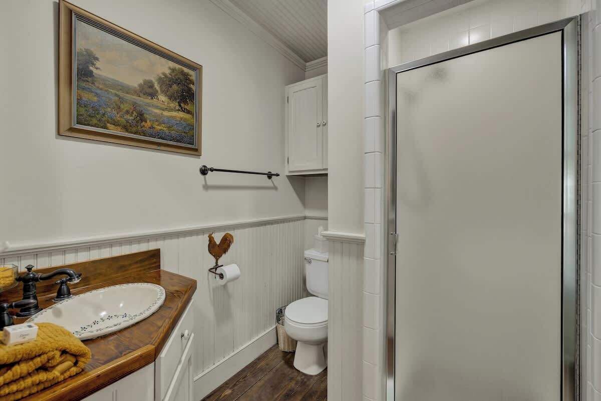 Un bagno con un mobile vanitario in legno, un lavandino bianco, un water e una cabina doccia.