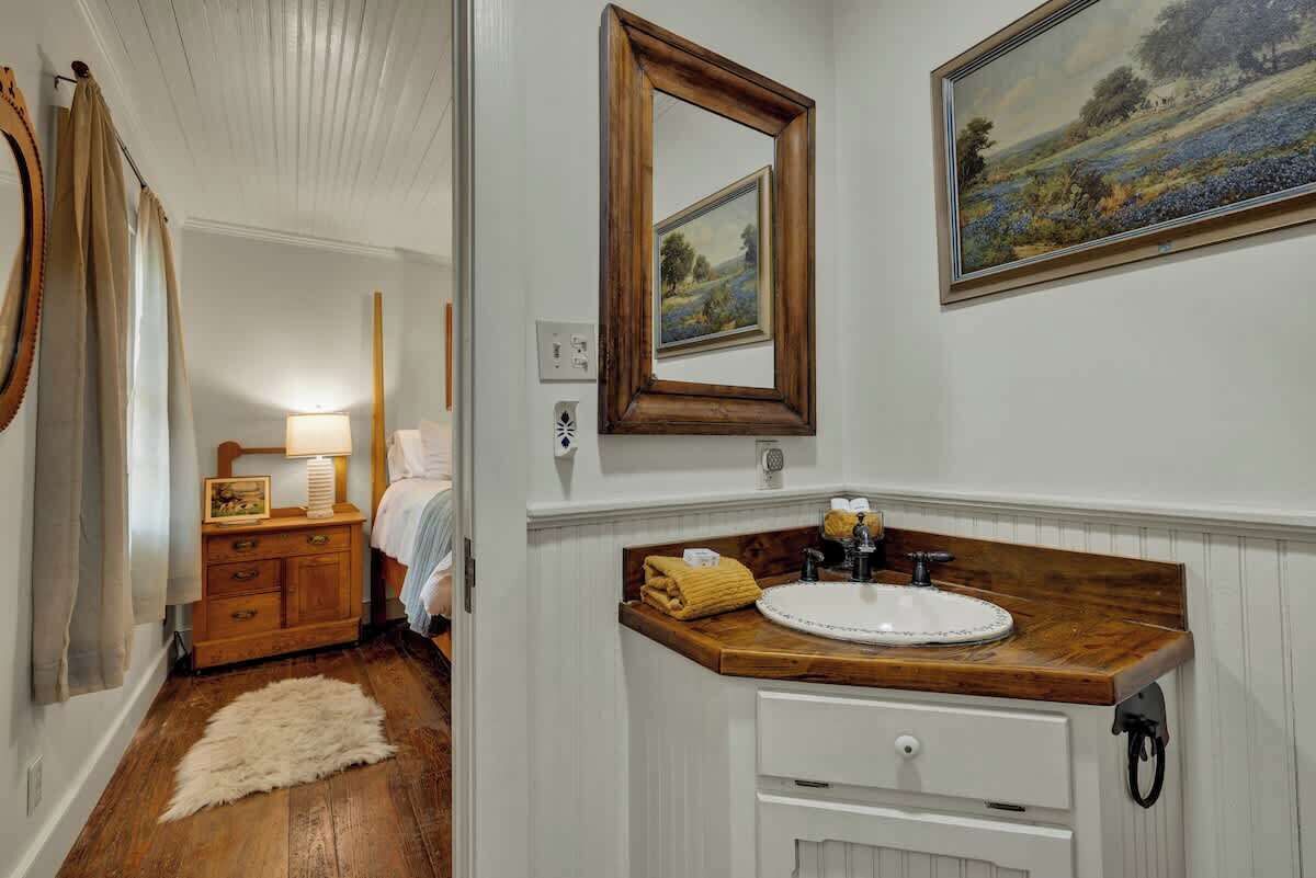 A bathroom with a wooden vanity, a white sink, and a mirror.