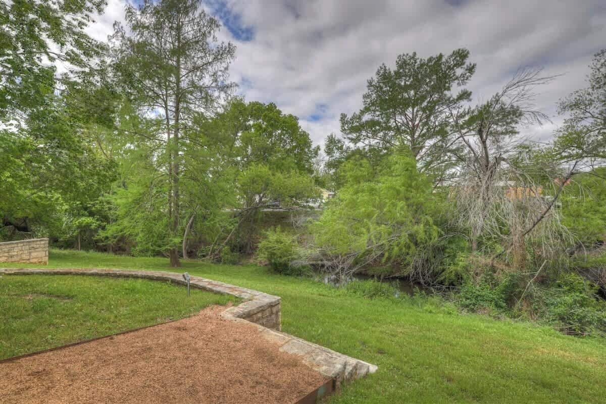 A landscaped garden with a curved stone bench, a small water feature, and dense greenery.