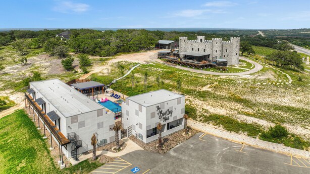 A modern hotel with a pool, a castle-like structure, and a parking lot. - The Bentley Hotel - Bill Murray Room - Pool View (Johnson City)