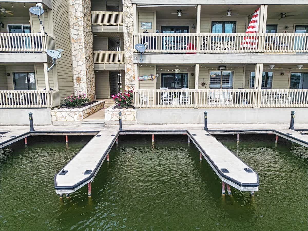 A multi-story hotel with balconies, a pool area with docked boats, and a flag.