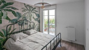 A bedroom with a bed, a large window, and a radiator. - 1 bedroom beautiful apartment in Gagny (Gagny)